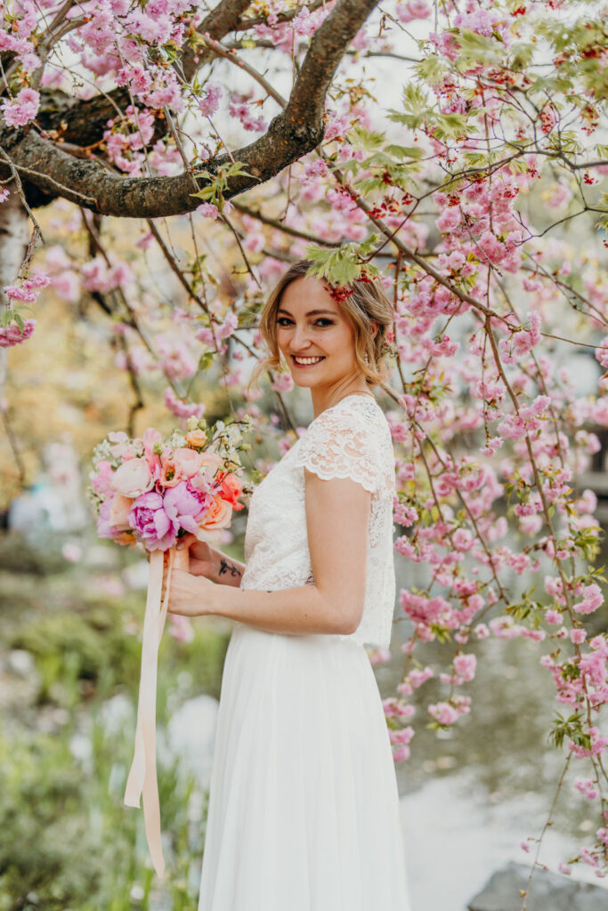 Braut mit Brautstrauß unter Kirschenbaum